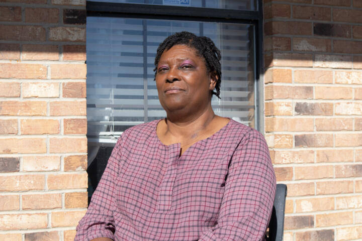 Photograph of Evelyn Washington, a Black woman sporting short braided hair and a dusty pink long-sleeved shirt.