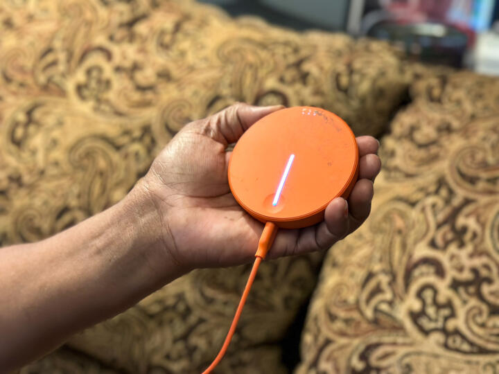 Closeup photograph of Evelyn Washington holding up her bright orange mobile hot spot