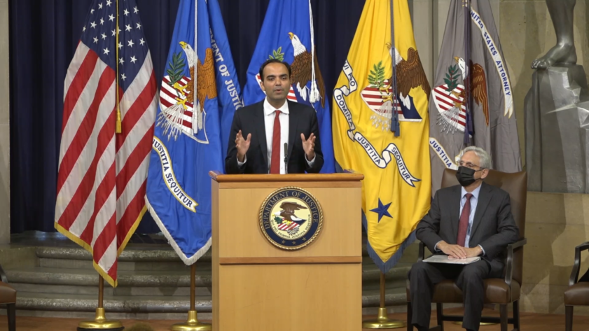 Rohit Chopra stands at a podium in the Department of Justice auditorium.